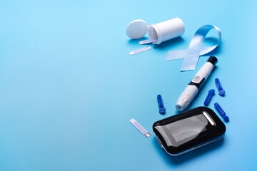 Diabetes awareness concept of ribbon glucose meter test strips and lancets on blue background