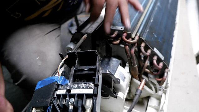 The process of disassembling a broken air conditioner by a home technician.