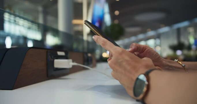 Female hands use cell phone and charge smartphone on charging station. close-up