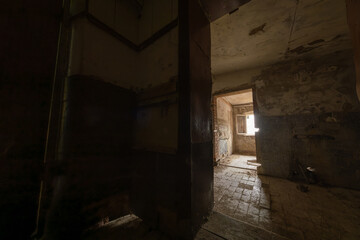Fototapeta na wymiar Doorways leading to shabby rooms from grungy corridor inside derelict building in daytime
