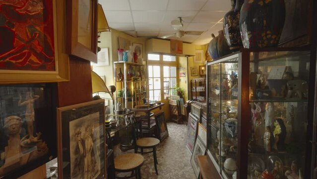 Wide angle view of glass showcases in antique store across from paintings and vases