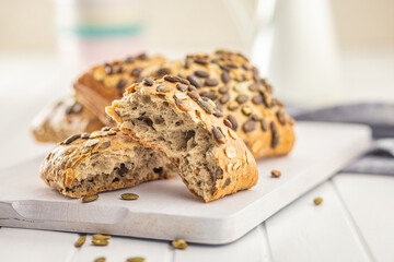 Whole grain bun with pumpkin seeds on cutting board.