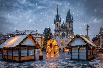 Beautiful winter view of the old town square of Prague, Czech Republic, with a christmas market and the famous Tyn Church with snow - obrazy, fototapety, plakaty