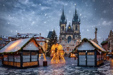 Tuinposter Beautiful winter view of the old town square of Prague, Czech Republic, with a christmas market and the famous Tyn Church with snow © moofushi