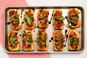 aerial view of rectangular tray holding six evenly spaced bruschetta, each topped with basil