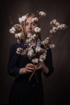 classic dark studio porrtait of woman holding braches of cotton snowball flowers