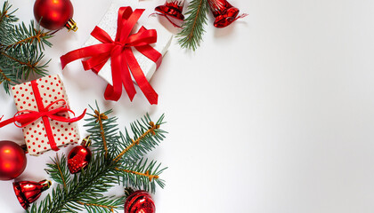 Presents, spruce tree branches, and red ornaments on a white backdrop. Captured from above with space for text