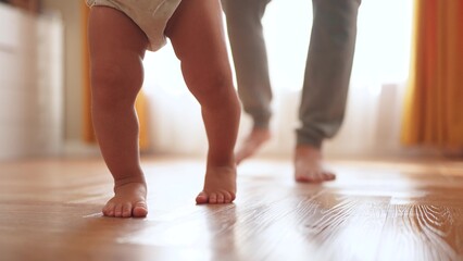 baby first steps. happy family a kid dream concept. father teaches baby daughter to take first...