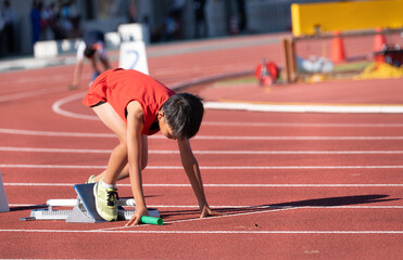 陸上大会でリレーを走る小学生の男の子