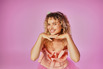 attractive blonde woman in tooth fairy costume looking happily at camera with hand under chin