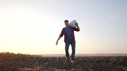 farmer working with sack in agricultural field. agriculture a business farm concept. farmer worker carries a bag with harvest at lifestyle sunset silhouette in agricultural field