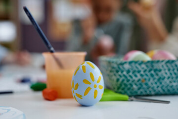 Closeup of painted Easter egg with cute design on table in arts and crafts class, copy space