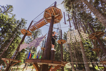 Young girl enjoying a thrilling zipline adventure in the forest.