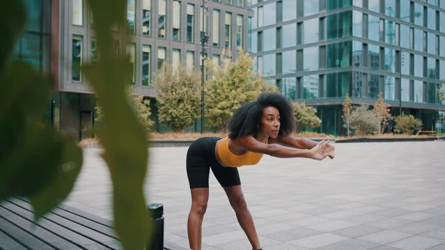 Adorable woman doing stretching exercise on urban streets