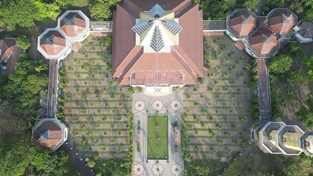 Aerial view of Masjid Kampus Universitas Gadjah Mada or UGM Mosque where Muslims worship with dome and tower surrounded by trees. Eid al-Fitr and Eid al-Adha. Bright Sunlight - During the day.
