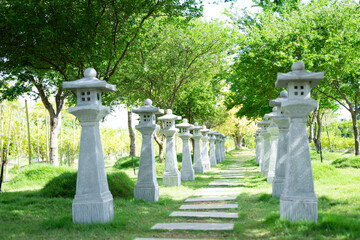 Classic street lamps on concrete poles line a walkway in the garden