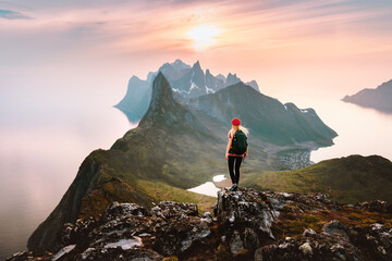 Traveler woman hiking solo in mountains of Norway outdoor activity travel summer vacations healthy lifestyle girl tourist enjoying sunset view on summit exploring Senja island - obrazy, fototapety, plakaty