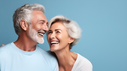 portrait of smiling elderly gray-haired couple couple happy pensioners man and woman with white perfect teeth isolated on blue background with copy space. Dental care. Dental prosthetics. Dentistry 