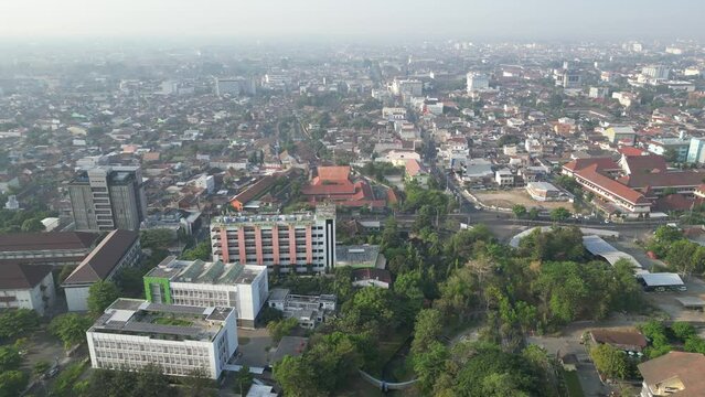 Aerial view of Jogja City with dense buildings development, crowded vehicles traffic in morning sunlight with smog or fog. Population density is displacing agricultural land and forests. Air Pollution