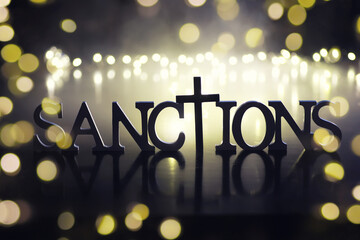 word sanctions spelled in letters on table made of wooden block letters with dramatic lighting and smoke