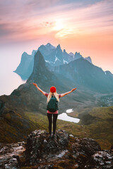 Traveler woman with backpack hiking in Norway girl raised arms alone on mountain top outdoor travel summer vacations active healthy lifestyle success motivation concept explore Senja island - obrazy, fototapety, plakaty