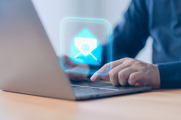 Concept of Email marketing, send e-mail or news letter, online working internet network. Male hand using a computer laptop typing on keyboard and surfing the internet on office table with email icon.