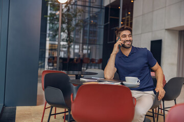 Smiling businessman talking by phone with client sitting in cozy coworking. High quality photo