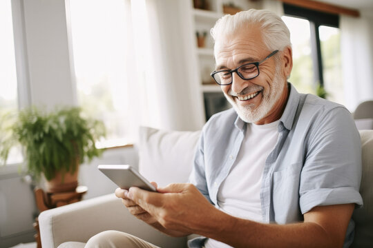 Portrait of a relaxed senior man laughing while using his smartphone at home. Modern lifestyle of the elderly people. 
