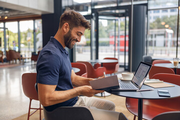 Smiling male architect is making notes during work on laptop in modern coworking space