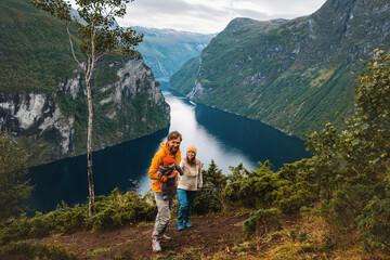 Family traveling in Norway sightseeing Geiranger fjord Father and mother with infant baby hiking outdoor active healthy lifestyle vacations parents with child tourists in mountains - obrazy, fototapety, plakaty