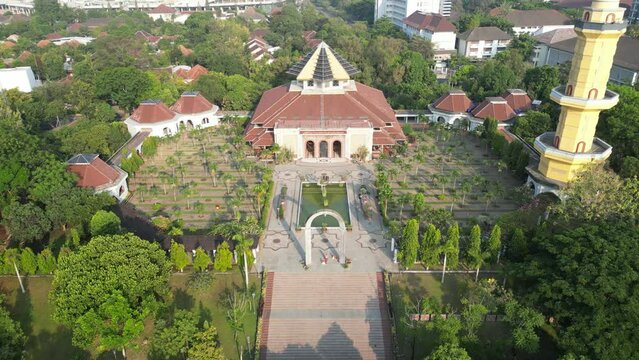Aerial view of Masjid Kampus Universitas Gadjah Mada or UGM Mosque where Muslims worship with dome and tower surrounded by trees. Eid al-Fitr and Eid al-Adha. Bright Sunlight - During the day.