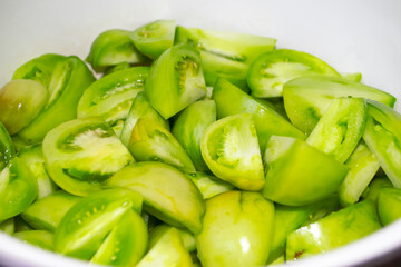 Green tomato salad. Green tomato fruits are cut into pieces. Processing of green tomatoes.