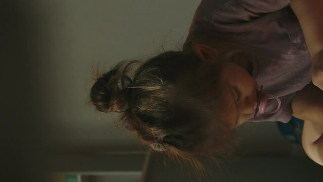 Beautiful happy girl child sucking a pacifier sitting on green sofa, playing.