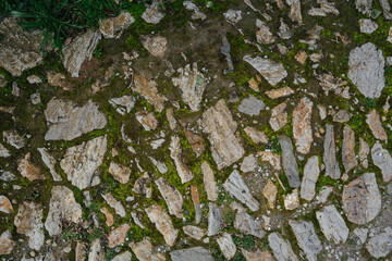 Ancient stone pavement overgrown with moss and grass, photo texture