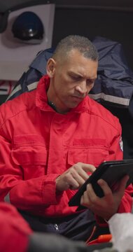 Tablet, paramedic and a man in an ambulance for emergency service or professional accident rescue. Technology, research and information with a first aid emt looking at an online medical report