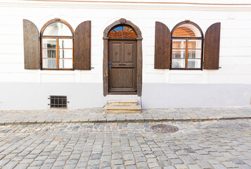 selective focus on a white wall with a wooden door and shutters on the windows