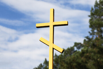 Orthodox cross isolated on sky. Cemetery metal gate cross background. Old, rusty metal faith symbol. East of Poland. Yellow paint metal gate. Orthodox forest graveyard. Entrance to cemetery.