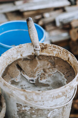 Tool, trowel in a bucket with sand, cement, water. Photography, building, concept.