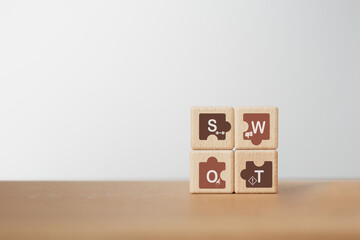 SWOT analysis and strategic planning technique concept. SWOT words inside jigsaw, means Strengths, Weaknesses, Opportunities and Threats on  wooden cube blocks including copy space