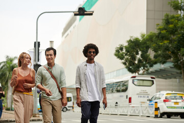 Group of adult friends walking in city on sunny day