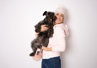 Smiling attractive young european woman in warm pink jumper isolated on white with a dog