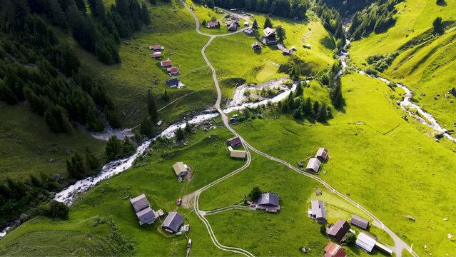Cinematic aerial view of peaceful idyllic Swiss village of &Auml;sch near Klausenpass in the Alps of Uri in Switzerland featuring Swiss farms and meadows and chalets in the green countryside   