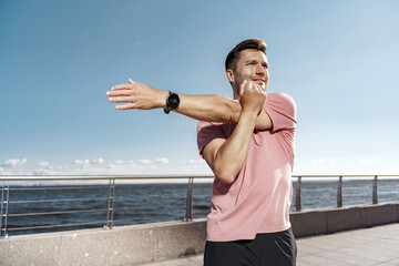 Fototapeta na wymiar A young man trains in sportswear. Fitness exercises, uses a running app. Portrait of a man using a sports watch.