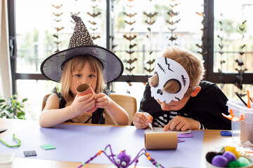  Cute brother and sister in Halloween costumes make festive crafts at the table. A master class on...