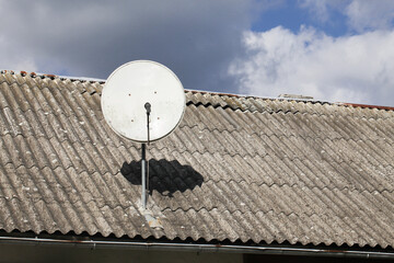 Tile roof antenna background. TV satelite dish old house roof. Countryside village architecture...