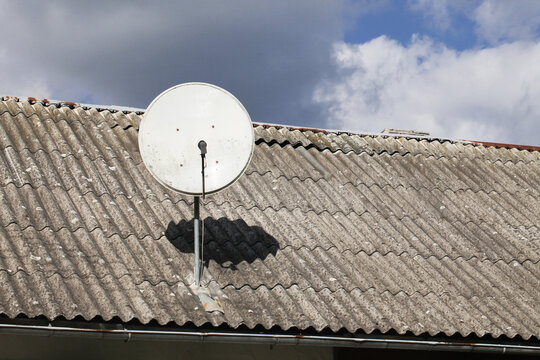 Tile roof antenna background. TV satelite dish old house roof. Countryside village architecture rooftop satelite. Television antenna mount.