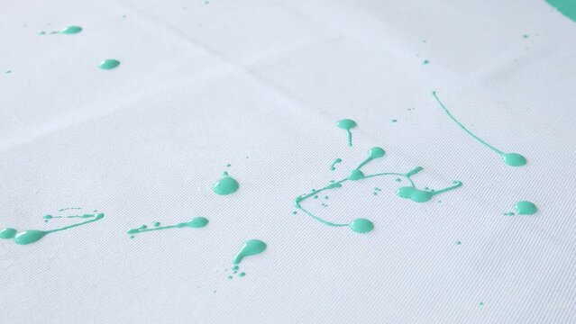 Green paint drips onto the floor. Painting process. Home renovation. Close-up.