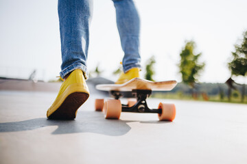 Fototapeta na wymiar Legs of a skater girl on the skateboard at the skate park in the city. skateboarding and fun concept