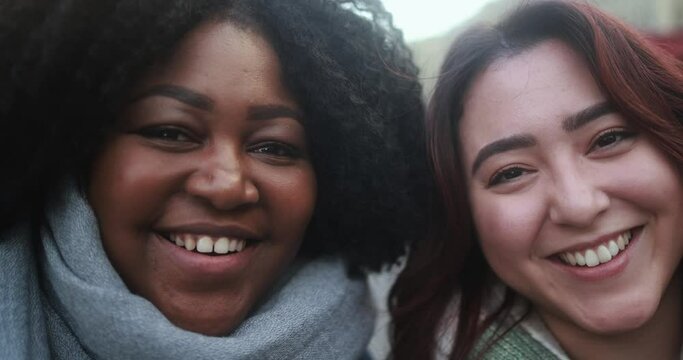 Happy young multiracial women smiling in front of camera during winter time outdoor - Diversity and friendship concept