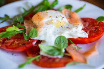 Cooked poached egg with herbs, lightly salted salmon and tomatoes with spices .